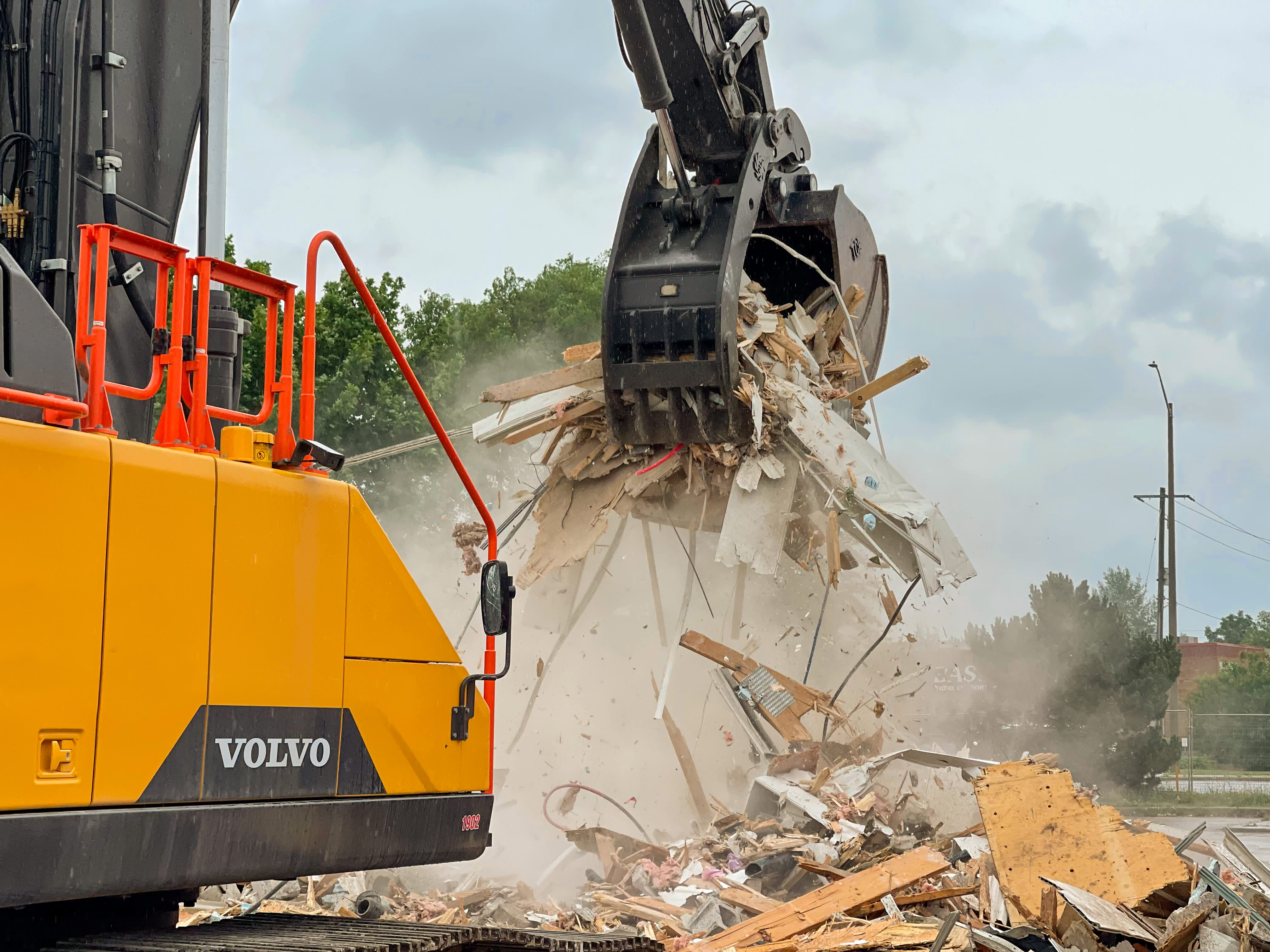 excavator with grapple bucket demolishing a building